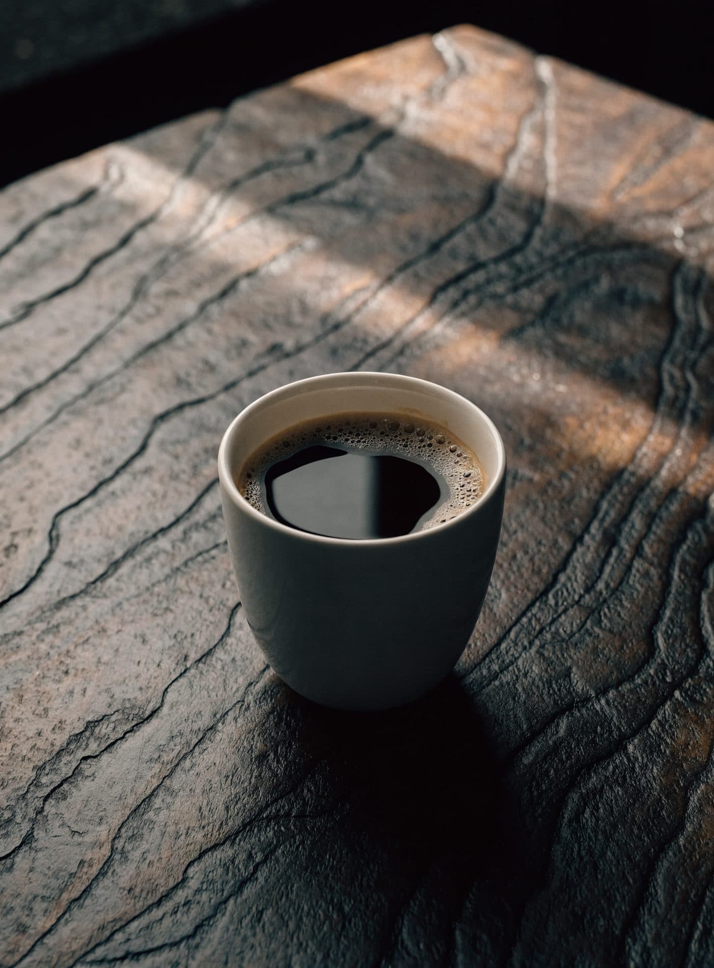 Plain ceramic cup on lava rock, illustration — not a named farm.